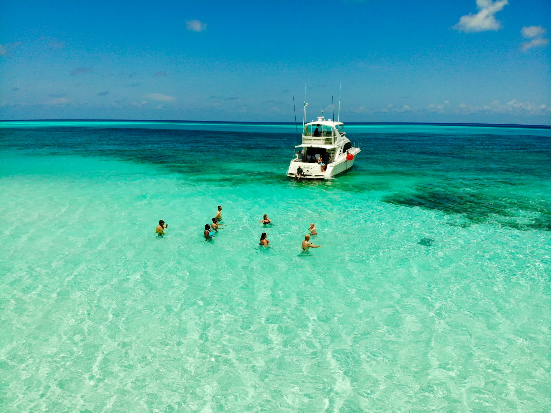 Travellers and a boat in the turquoise shallows of El Cielo, Cozumel; destination photograph